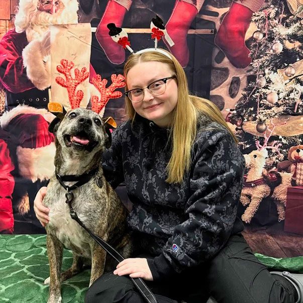 smiling girl with her dog in Christmas accessories